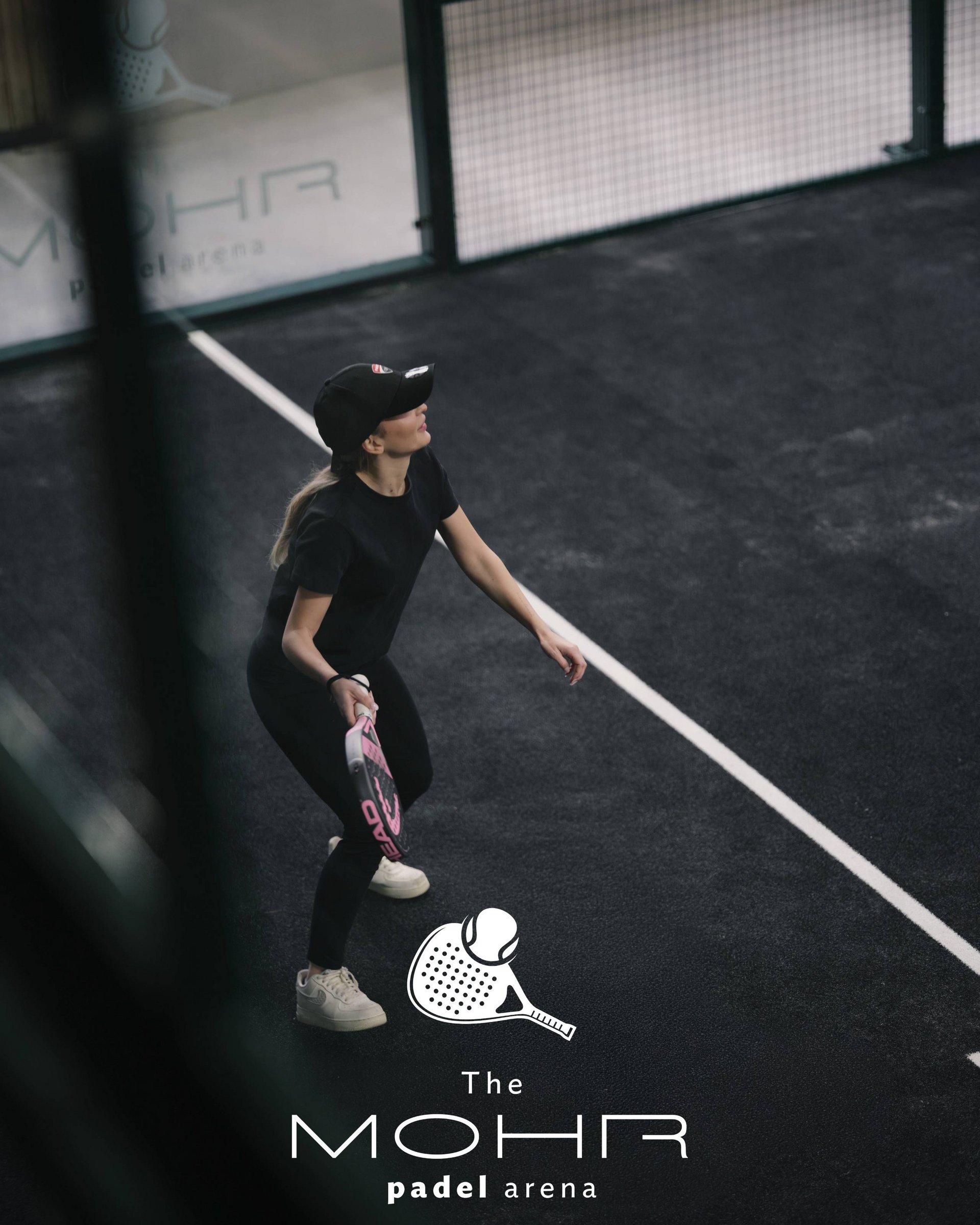 Wellness und Luxus: Ihr Hotel in Tirol Frau spielt Padel auf dunklem Platz mit Schläger und Ball