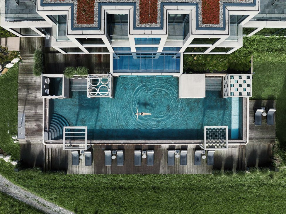 Großzügig und exklusiv: Ihr Wellnessurlaub in Tirol Drohnenaufnahme eines modernen Pools mit Person, die entspannt schwimmt