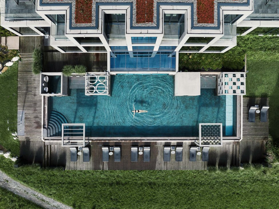 Großzügig und exklusiv: Ihr Wellnessurlaub in Tirol Drohnenaufnahme eines modernen Pools mit Person, die entspannt schwimmt