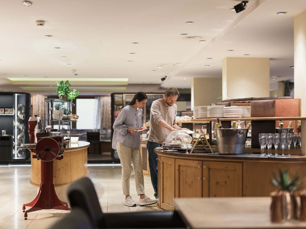 MOHR Genuss im Sporthotel in Österreich Ein Paar nimmt Essen an einem Buffet in einem Restaurant