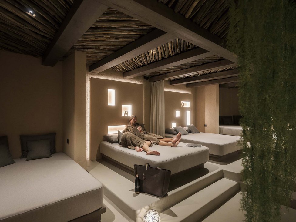 Großzügig und exklusiv: Ihr Wellnessurlaub in Tirol Paar entspannt auf Bett in gedämpft beleuchtetem Spa-Ruheraum