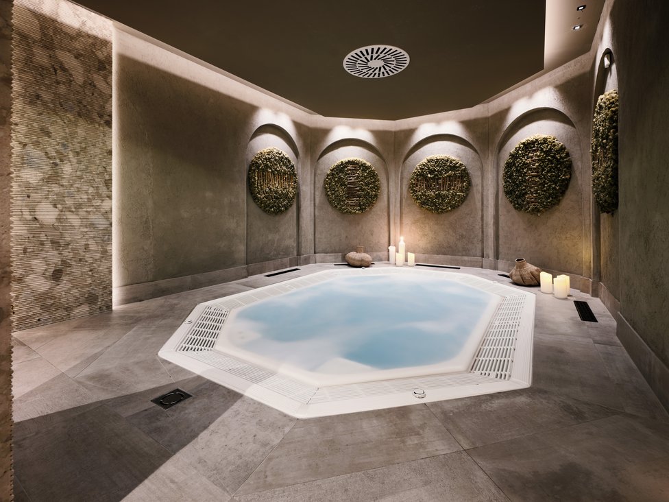 Großzügig und exklusiv: Ihr Wellnessurlaub in Tirol Moderner Wellnessbereich mit beleuchtetem Whirlpool und Wanddekorationen