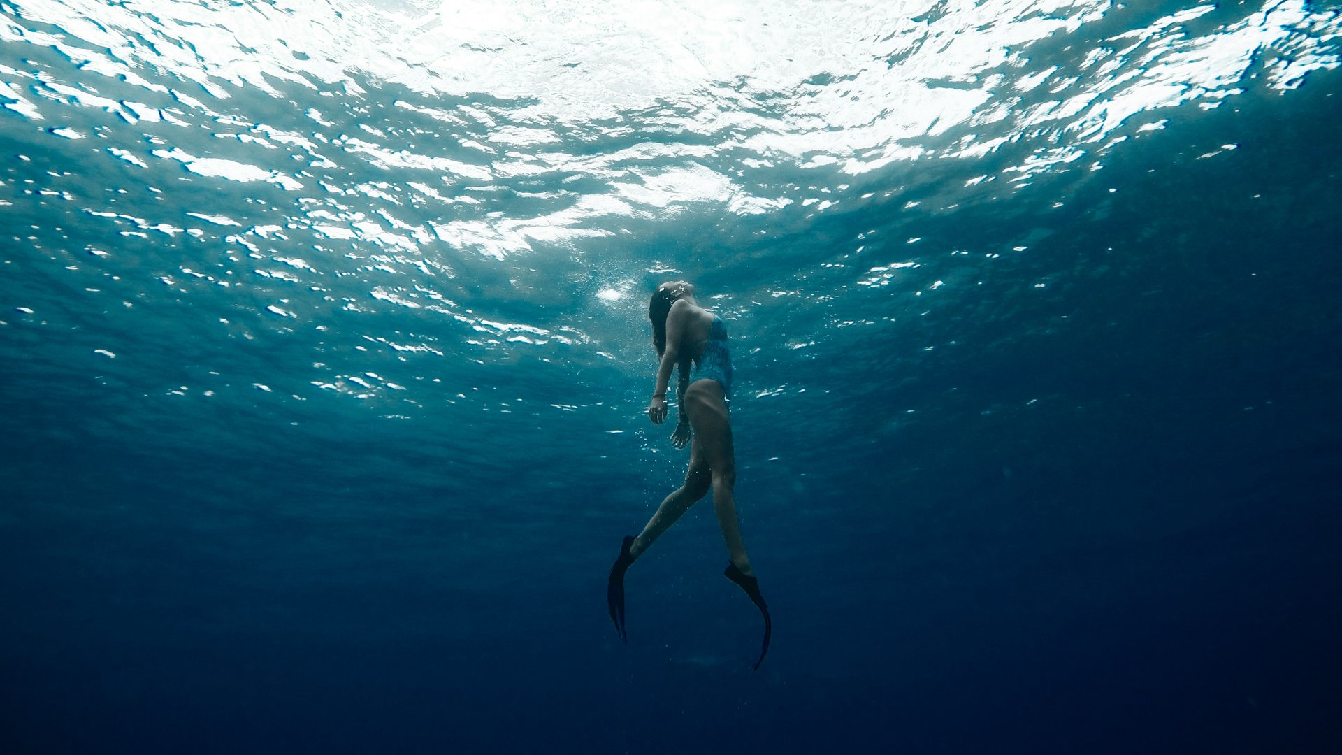 Ein Hotel mit Pool in Tirol – und zwei Badeseen Taucher mit Flossen schwimmt unter Wasser zum hellen Wasserspiegel