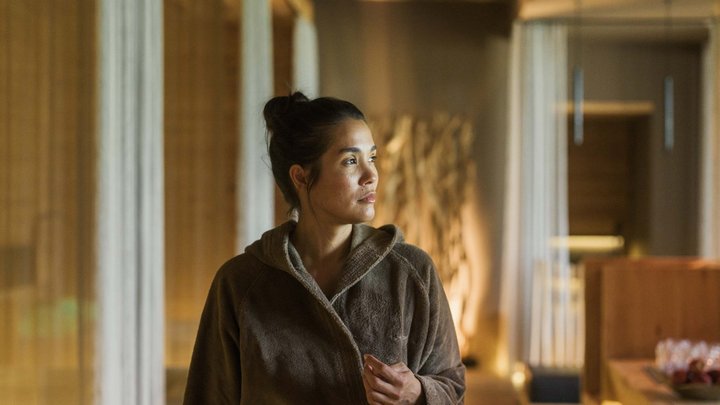 Wellness und Luxus: Ihr Hotel in Tirol Frau im braunen Bademantel schaut nachdenklich in einem warm beleuchteten Raum