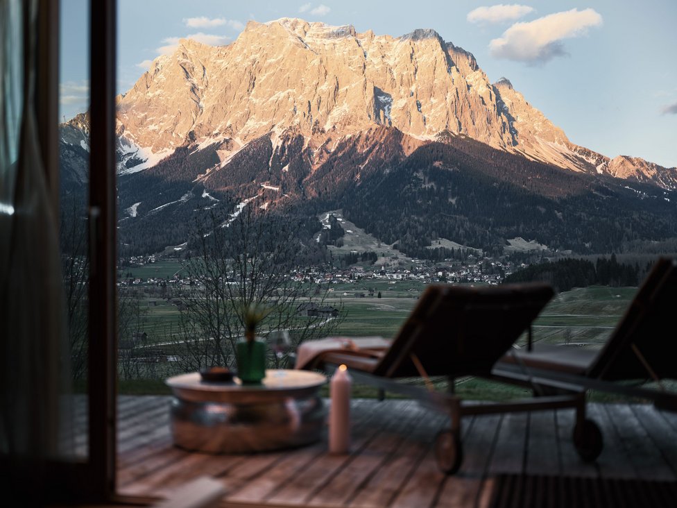 Wellness und Luxus: Ihr Hotel in Tirol Blick auf sonnenbeschienenen Berg und Tal von Terrasse mit Liegestühlen