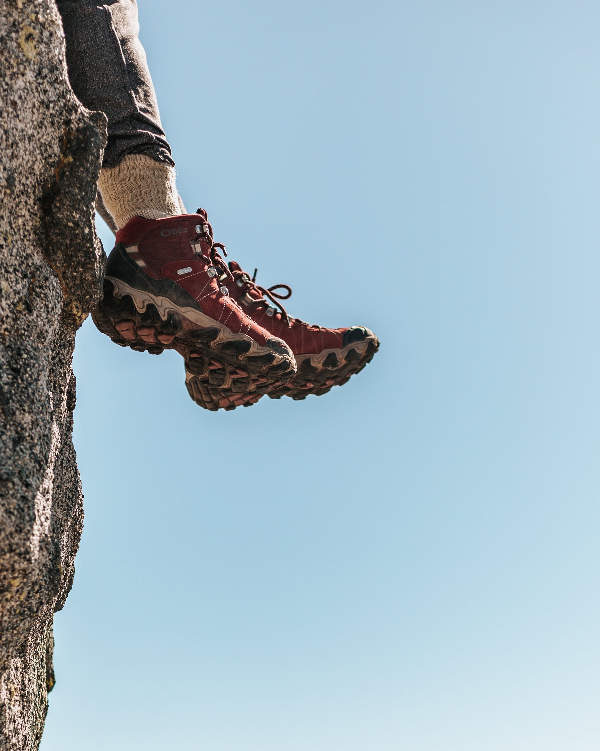 Aktivurlaub in Lermoos in Österreich Wanderer mit roten Schuhen sitzt am Felsenrand mit Bergkulisse im Hintergrund