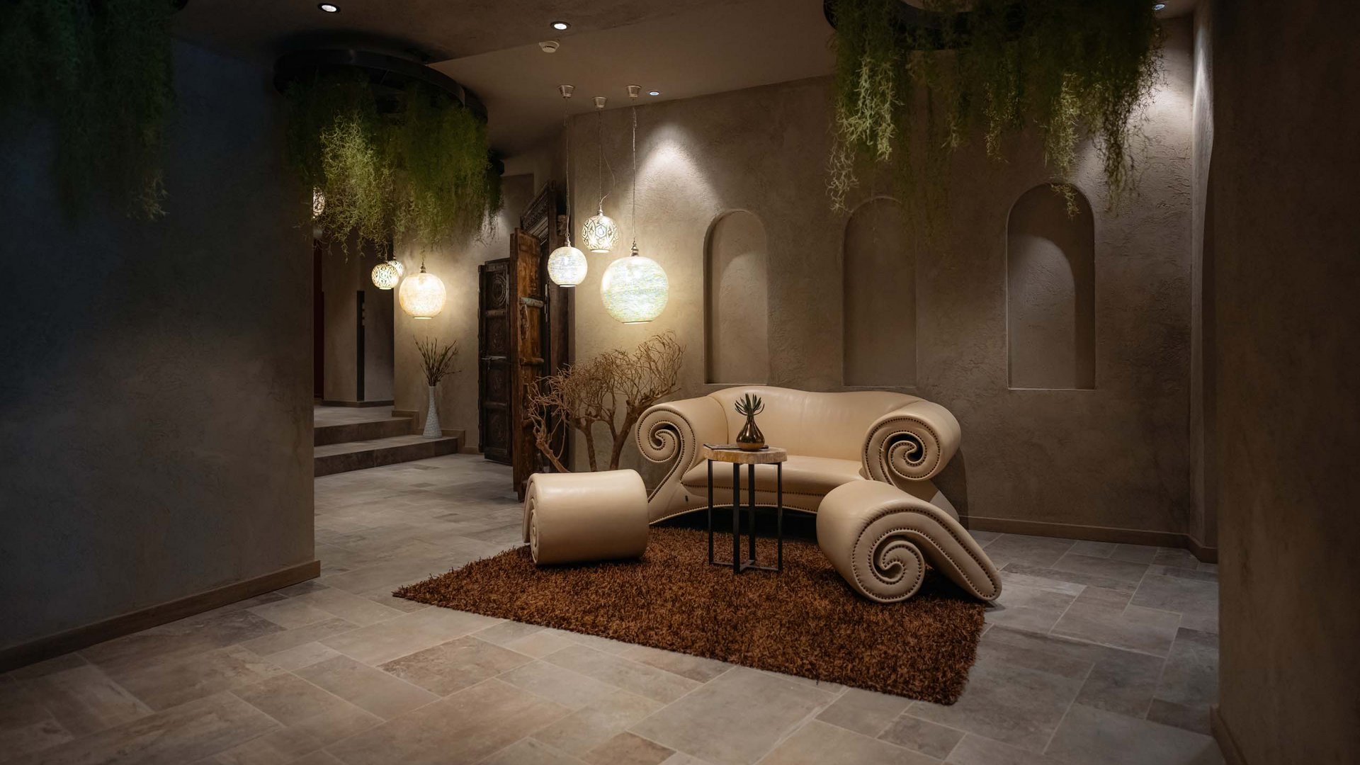 MOHR life resort Bildergalerie Elegantes Wohnzimmer mit einzigartigem Sofa, Teppich und hängenden Pflanzen