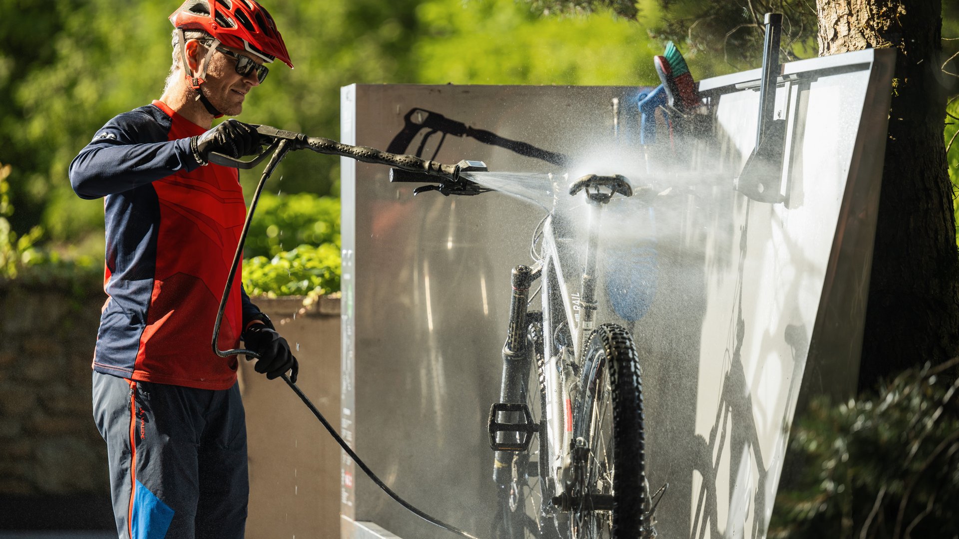 MOHR life resort Bildergalerie Mann wäscht Mountainbike mit Hochdruckreiniger im Freien