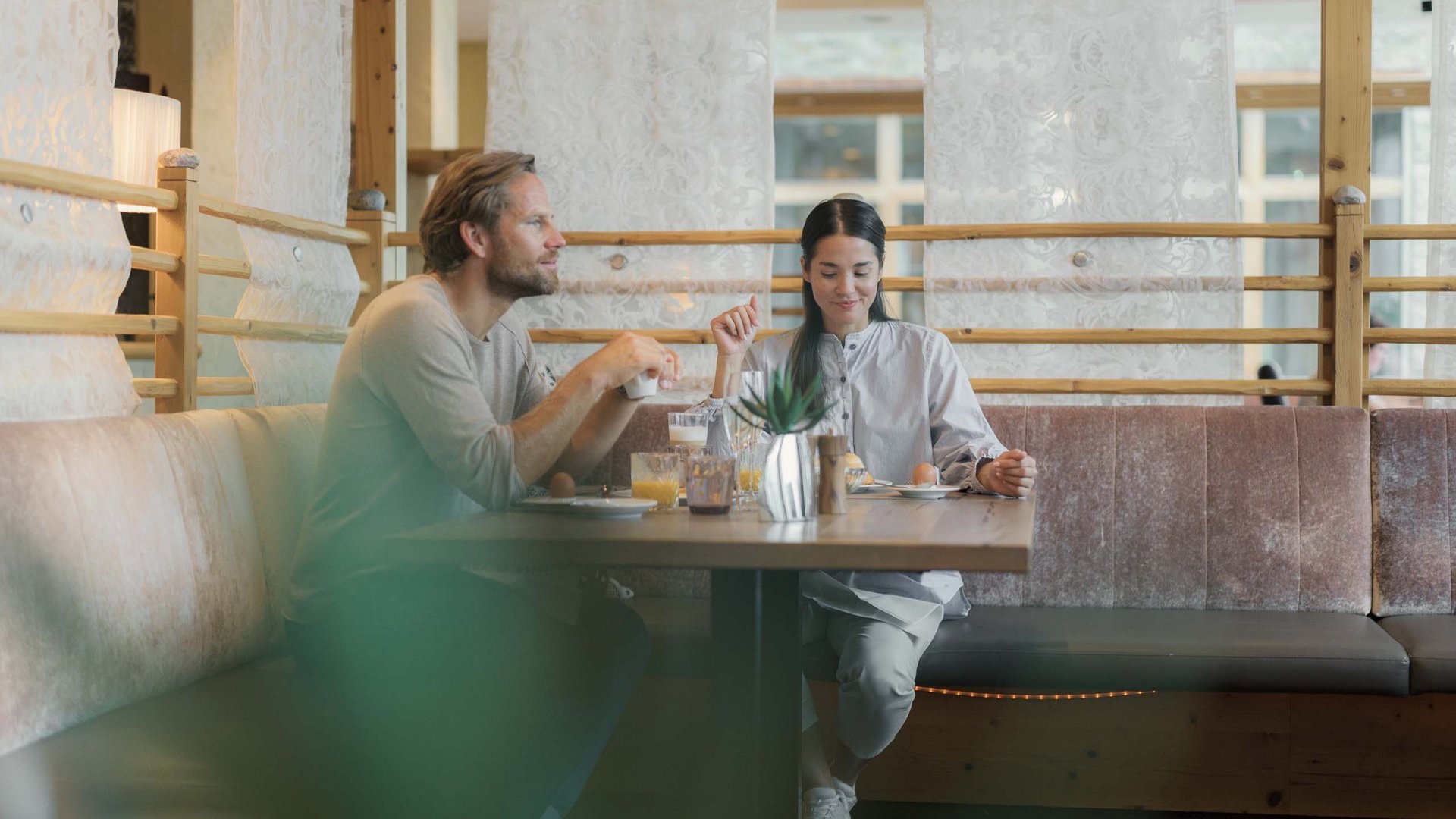 MOHR life resort Bildergalerie Paar frühstückt gemütlich an einem Holztisch in einem Café