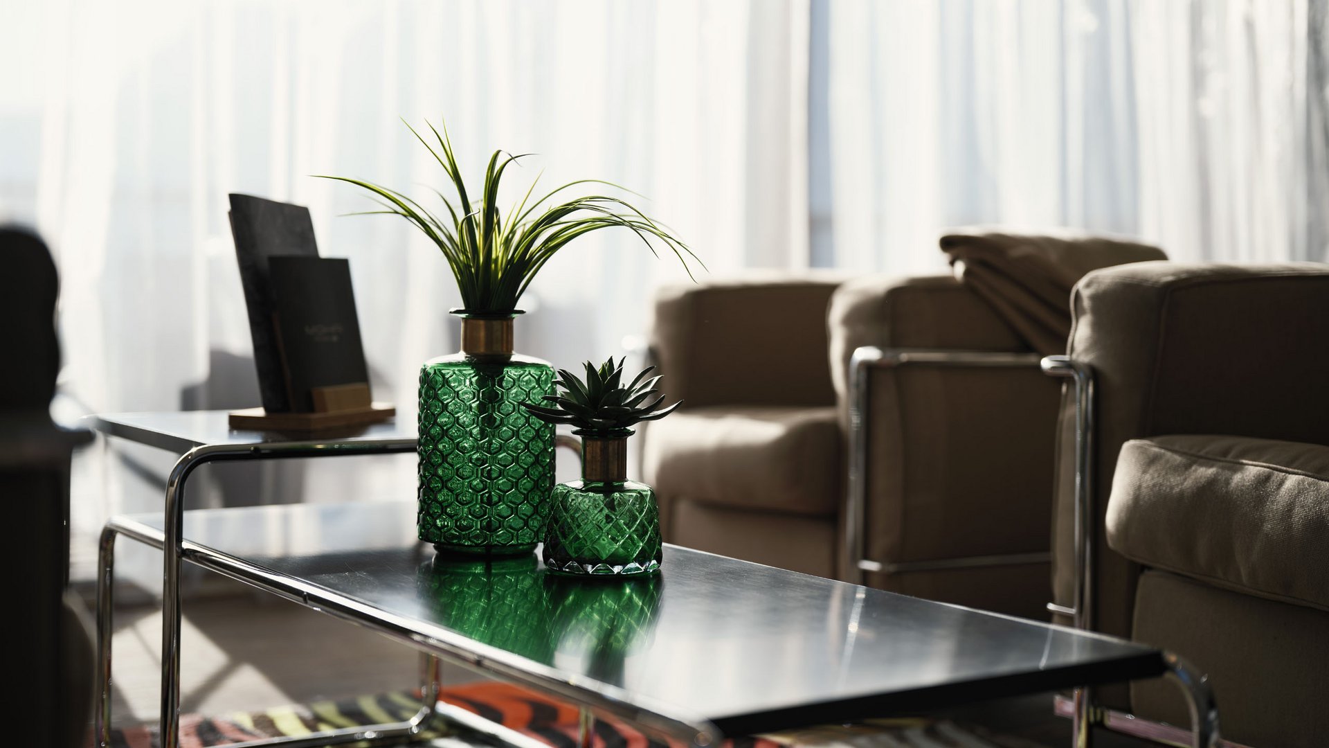 MOHR life resort Bildergalerie Grünes Glas mit Pflanzen auf modernem Tisch im Wohnzimmer mit Sesseln
