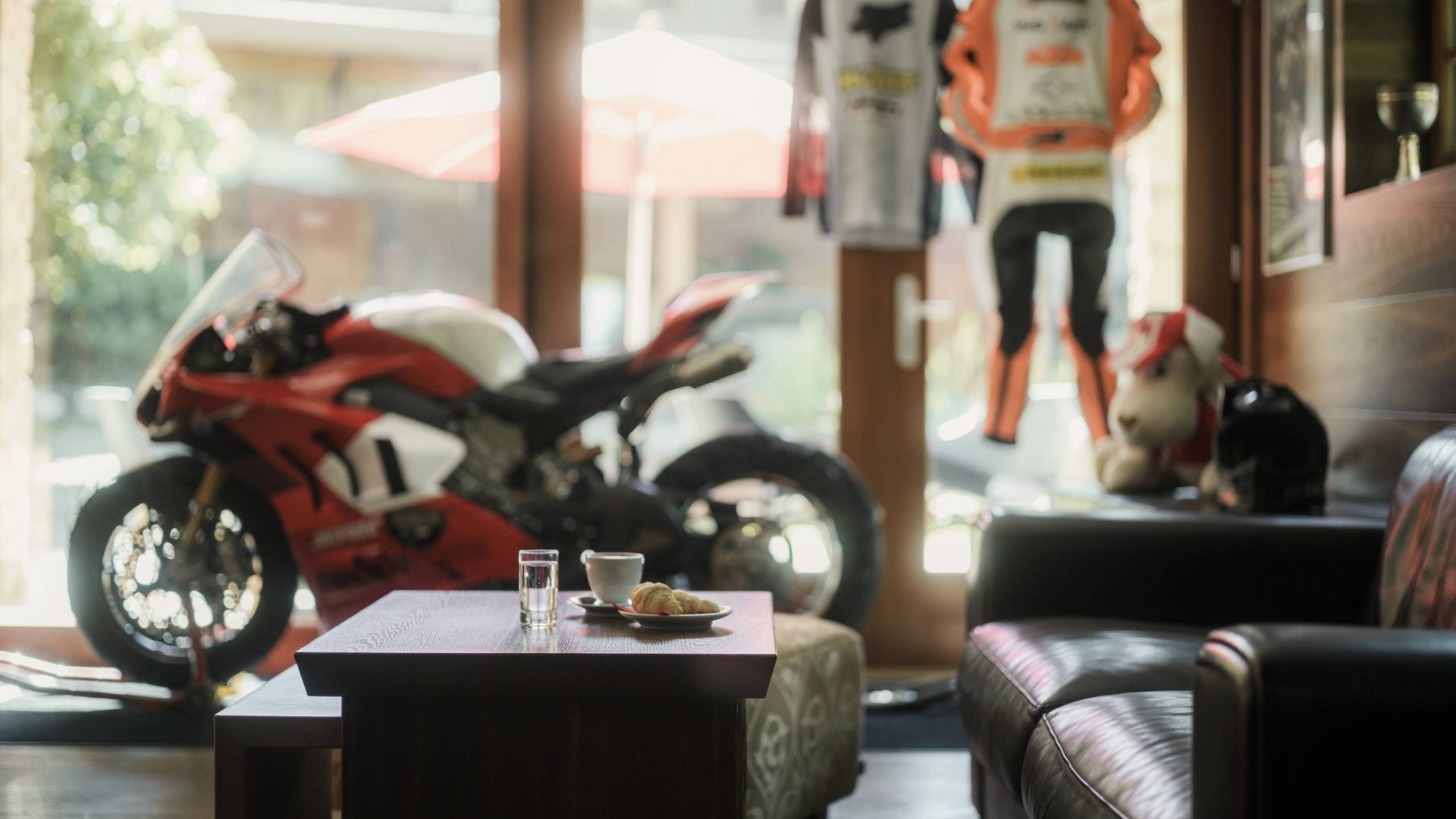 MOHR life resort Bildergalerie Sportmotorrad in Wohnzimmer mit Kaffee und Croissant auf Tisch