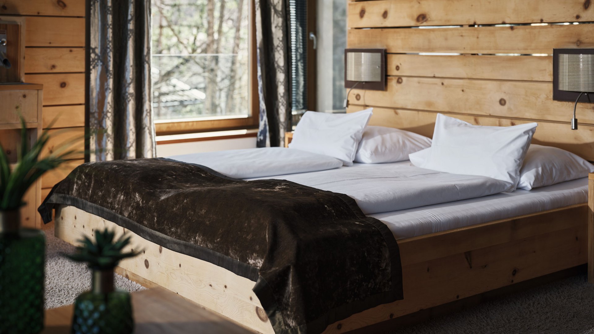 MOHR life resort Bildergalerie Gemütliches Schlafzimmer mit Holzmöbeln und großer Fensterfront