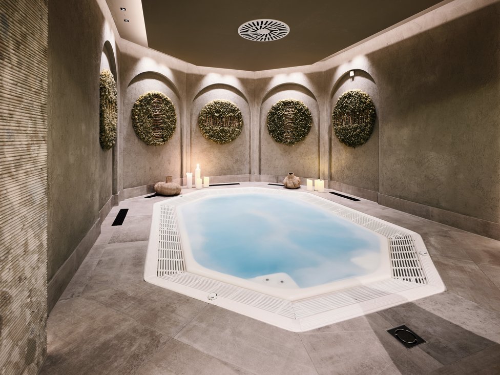 Wellness und Luxus: Ihr Hotel in Tirol Moderner Spa-Bereich mit achteckigem Whirlpool und dekorativen Wandpflanzen