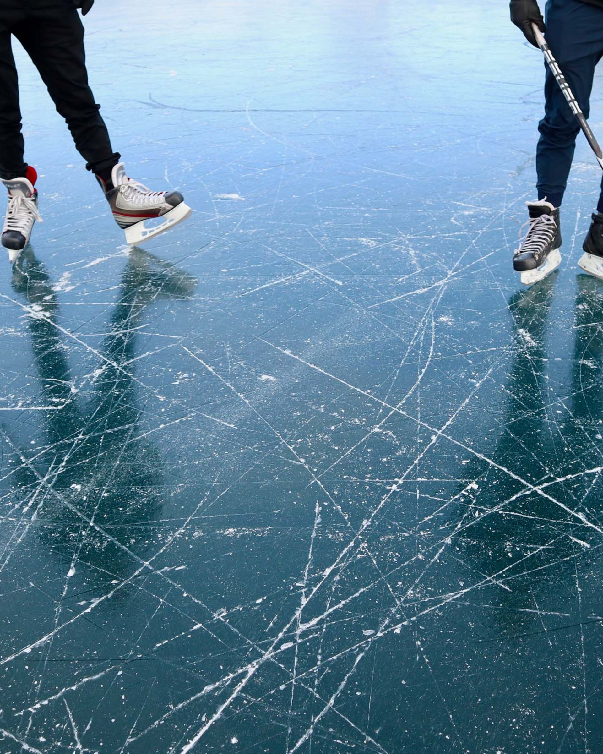Winterurlaub in Lermoos auf dem Eis Drei Personen spielen Eishockey auf einer stark zerkratzten Eisfläche
