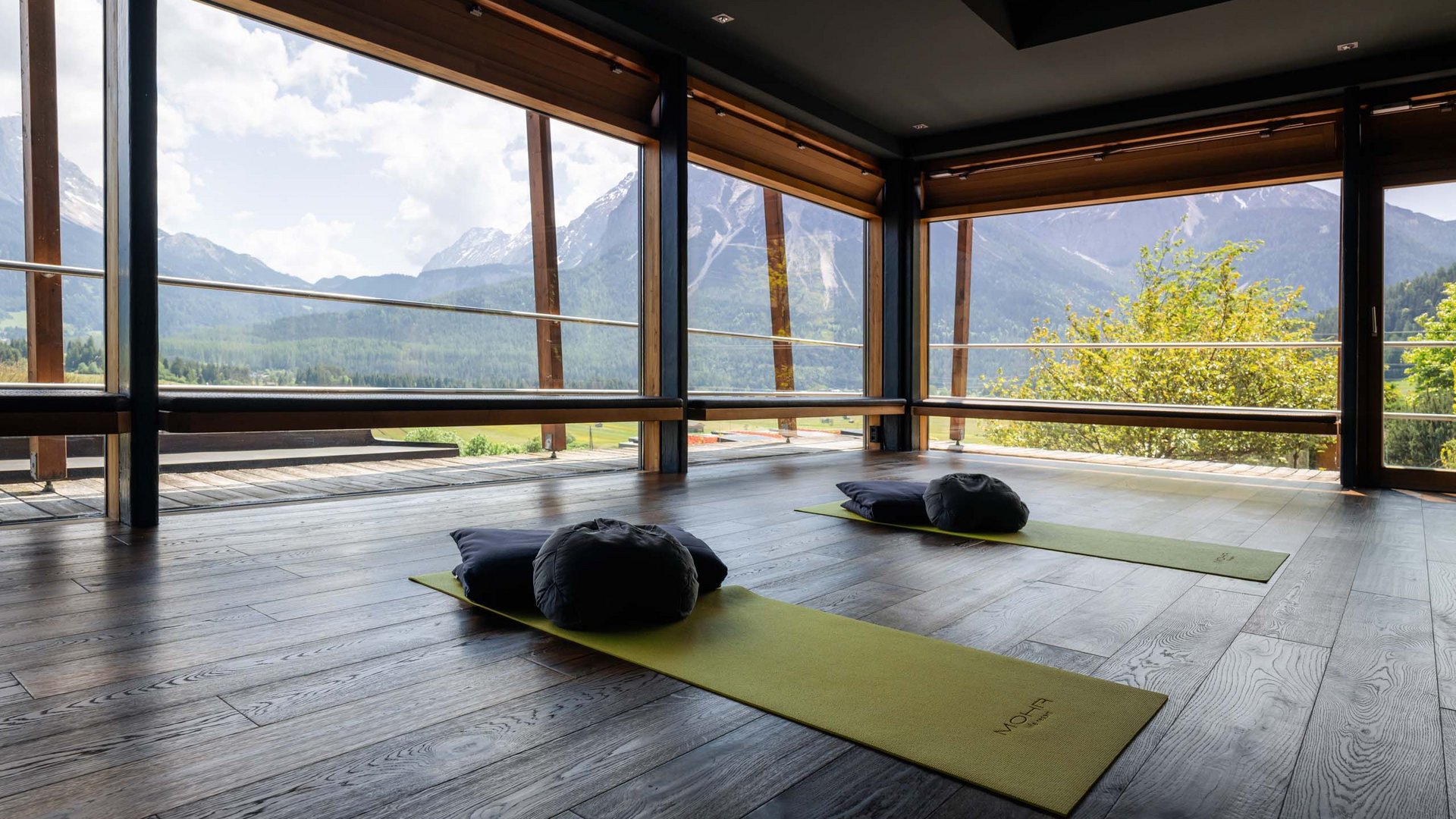 MOHR life resort Bildergalerie Yoga-Raum mit Blick auf Berge und zwei Matten mit Kissen