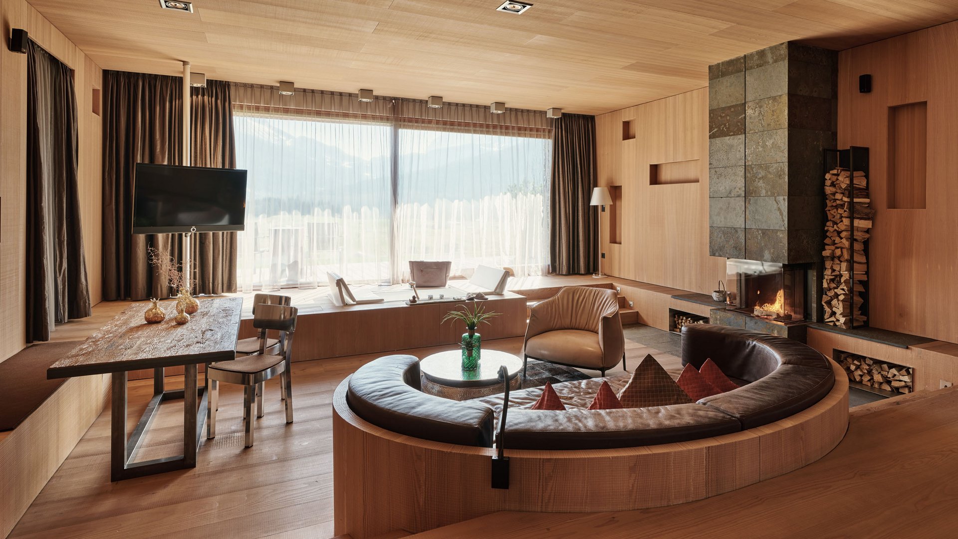 MOHR life resort Bildergalerie Modernes Wohnzimmer mit großem Fenster, Kamin und rundem Ledersofa