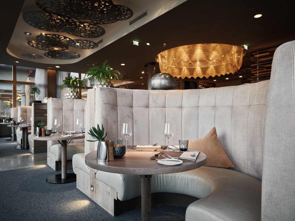 MOHR Genuss im Sporthotel in Österreich Gemütliche runde Sitzgruppe in einem modernen Restaurant mit gedecktem Tisch