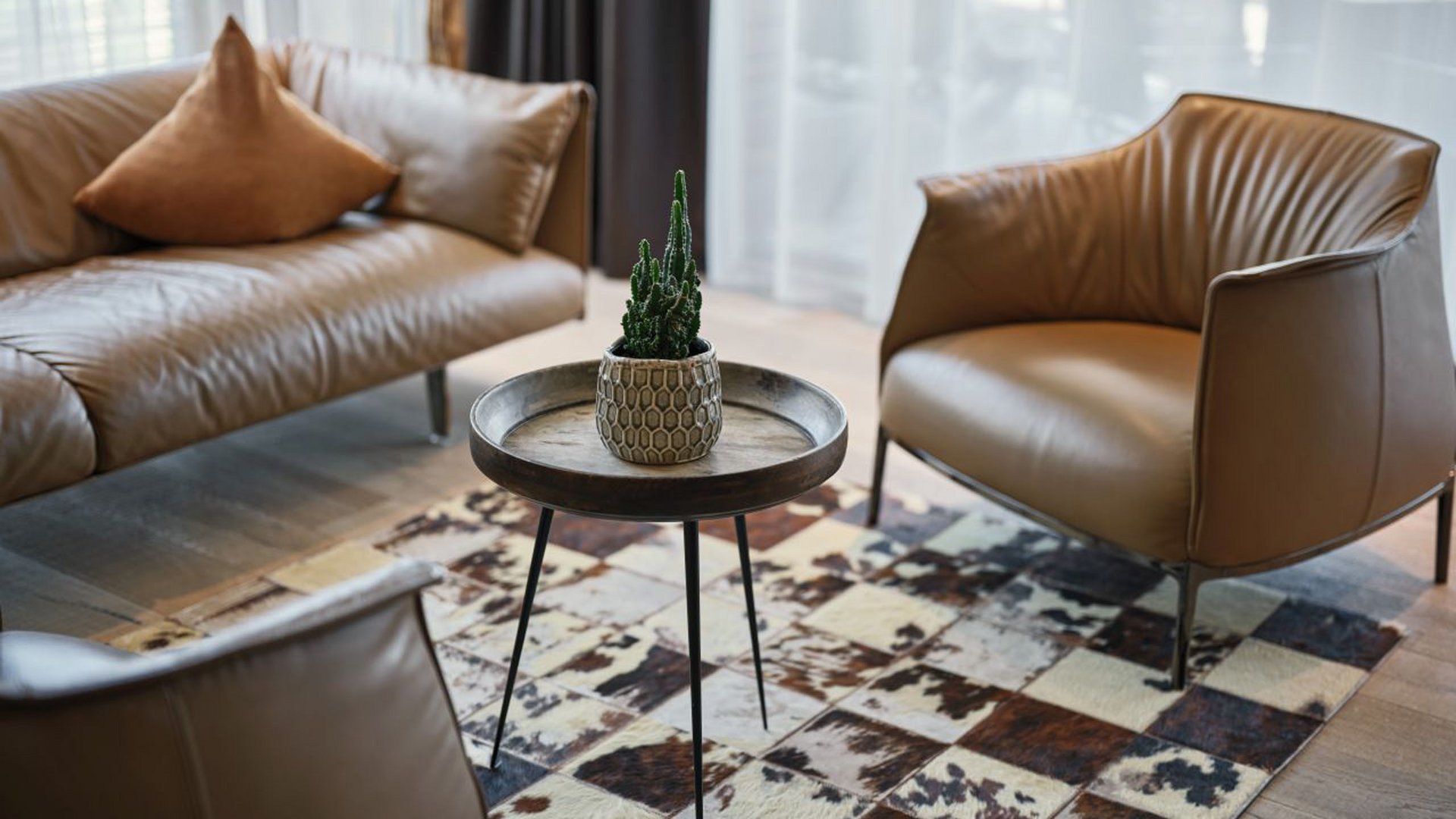 MOHR life resort Bildergalerie Wohnzimmer mit braunen Ledermöbeln und kleinem Tisch mit Pflanze