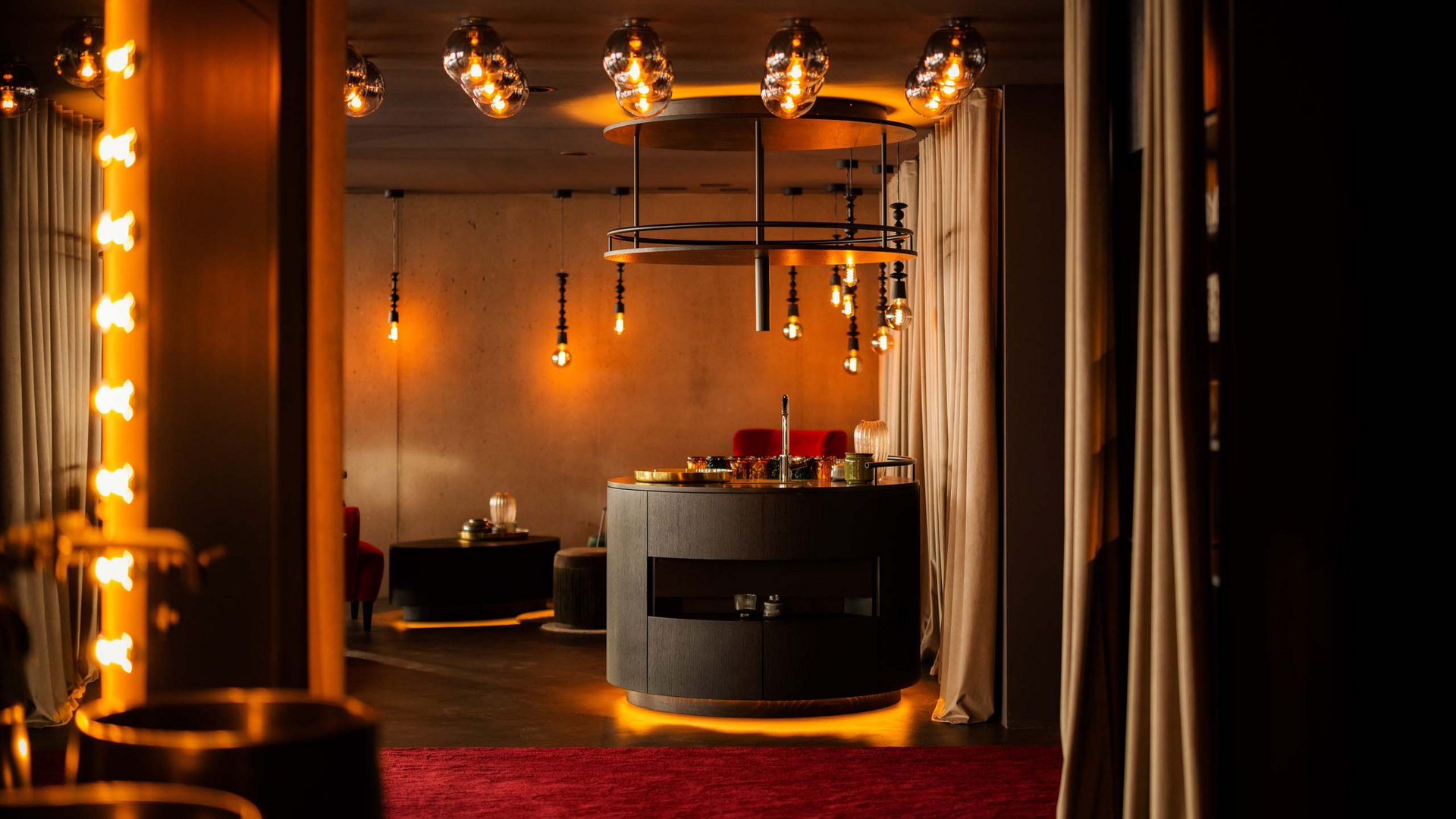 MOHR life resort Bildergalerie Stilvoll beleuchteter Raum mit runder Bar und rotem Teppich