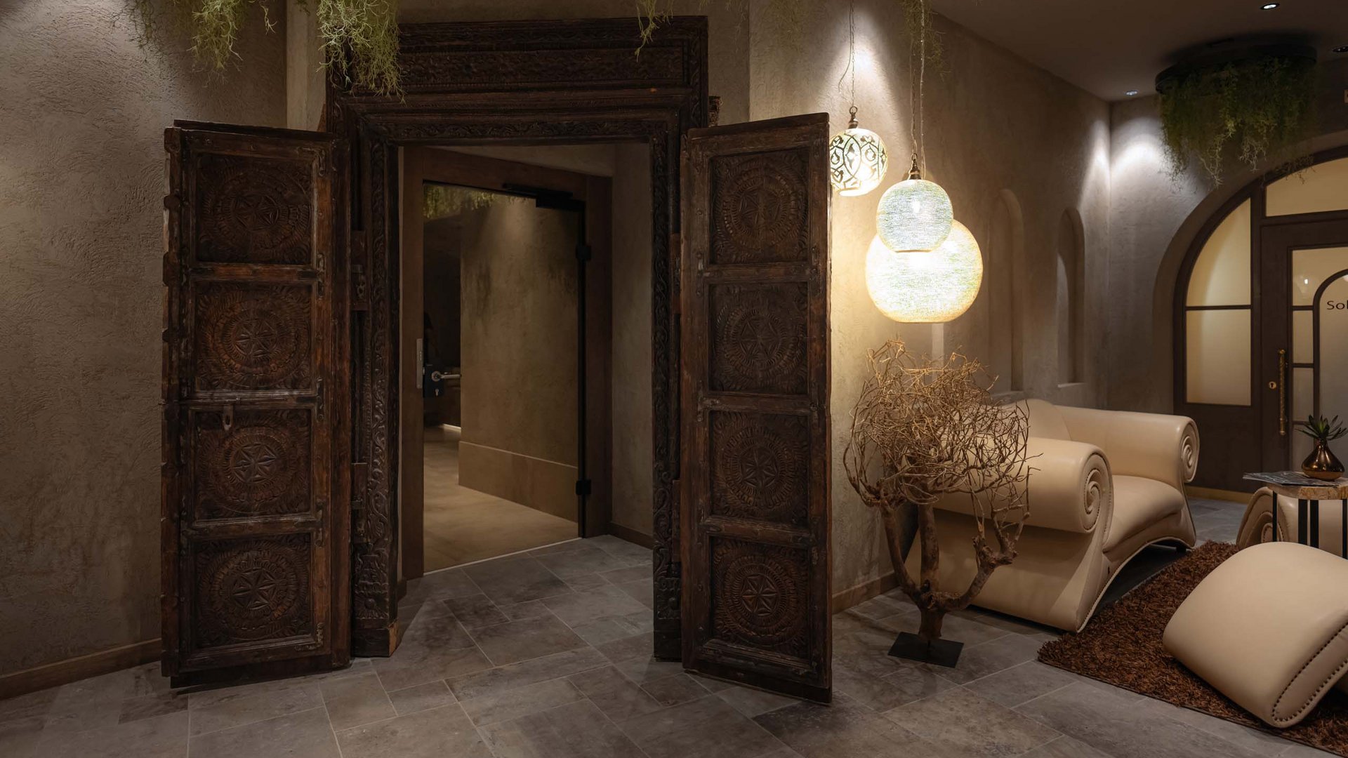 MOHR life resort Bildergalerie Eleganter Raum mit geschnitzter Holztür und beigen Ledermöbeln