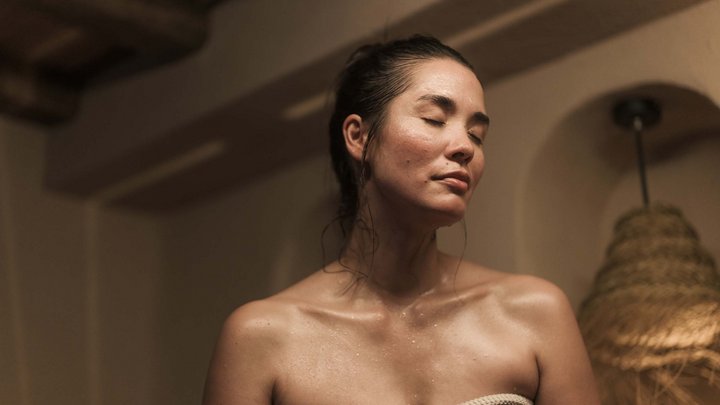 Wellness und Luxus: Ihr Hotel in Tirol Frau entspannt mit geschlossenen Augen nach dem Duschen