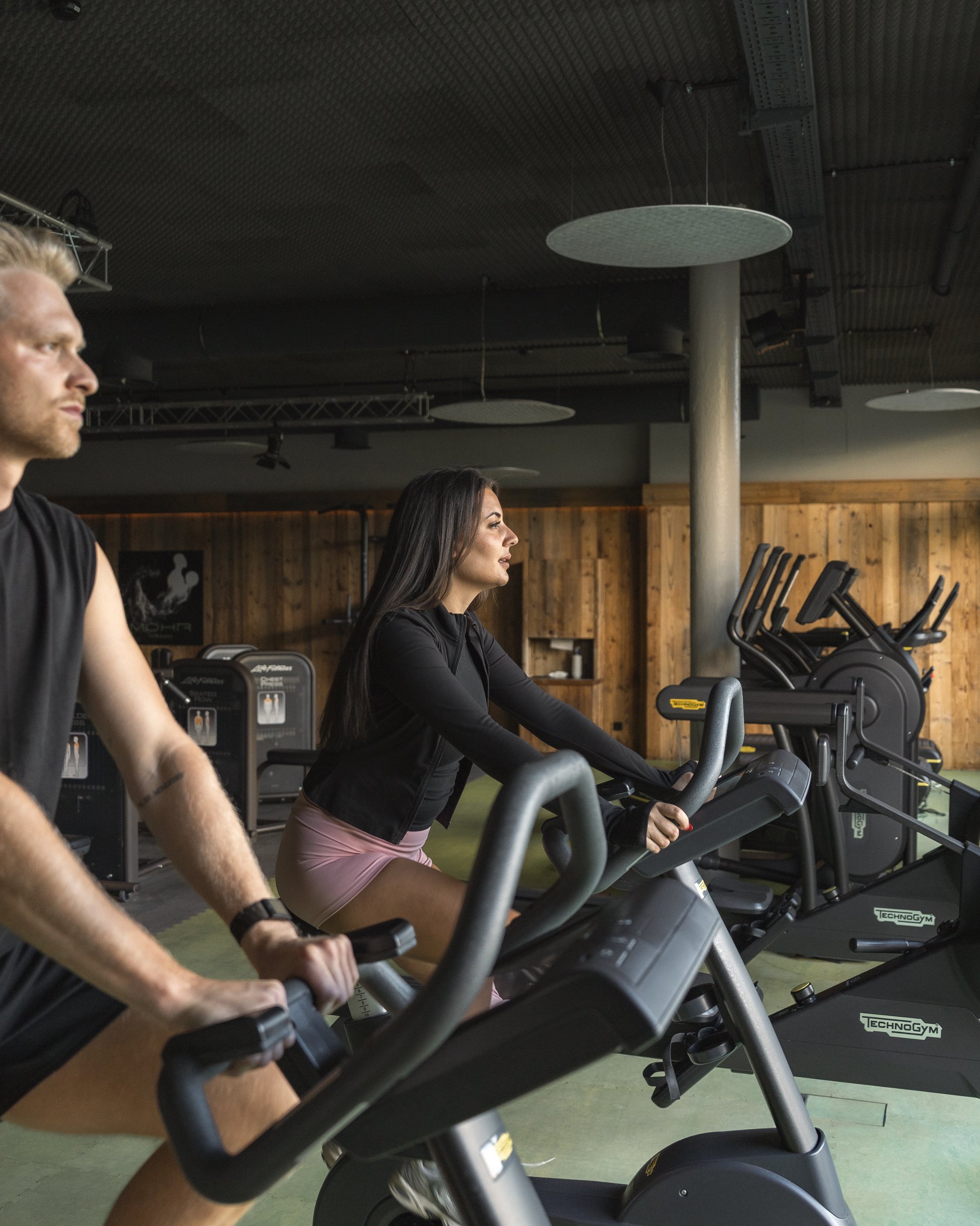 Wellness und Luxus: Ihr Hotel in Tirol Zwei Personen trainieren auf Fahrradergometern in einem Fitnessstudio
