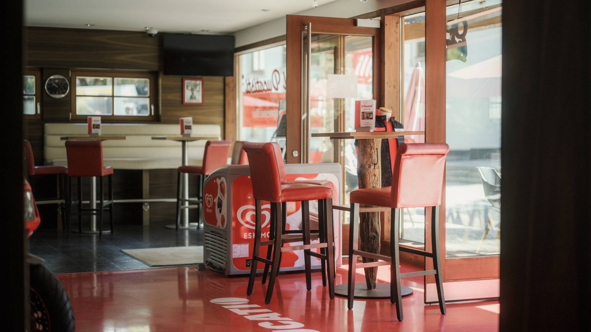 MOHR life resort Bildergalerie Innenansicht eines Cafés mit roten Barhockern und Tischen bei Tageslicht