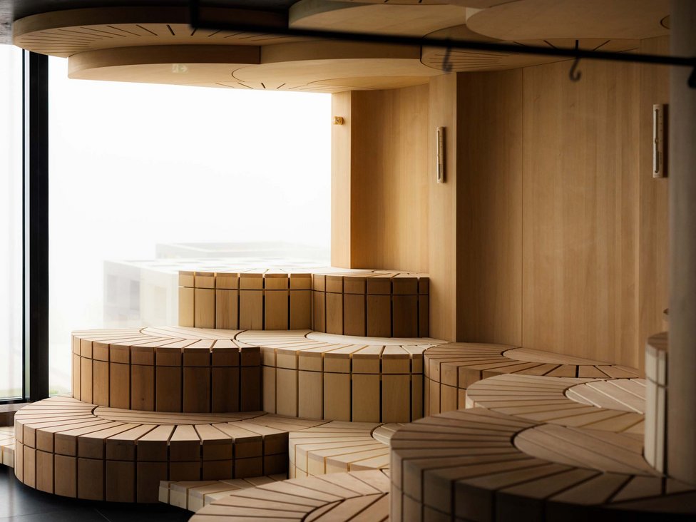 Großzügig und exklusiv: Ihr Wellnessurlaub in Tirol Modernes, gestuftes Holzsofa in hellen natürlichen Tönen vor Fenster