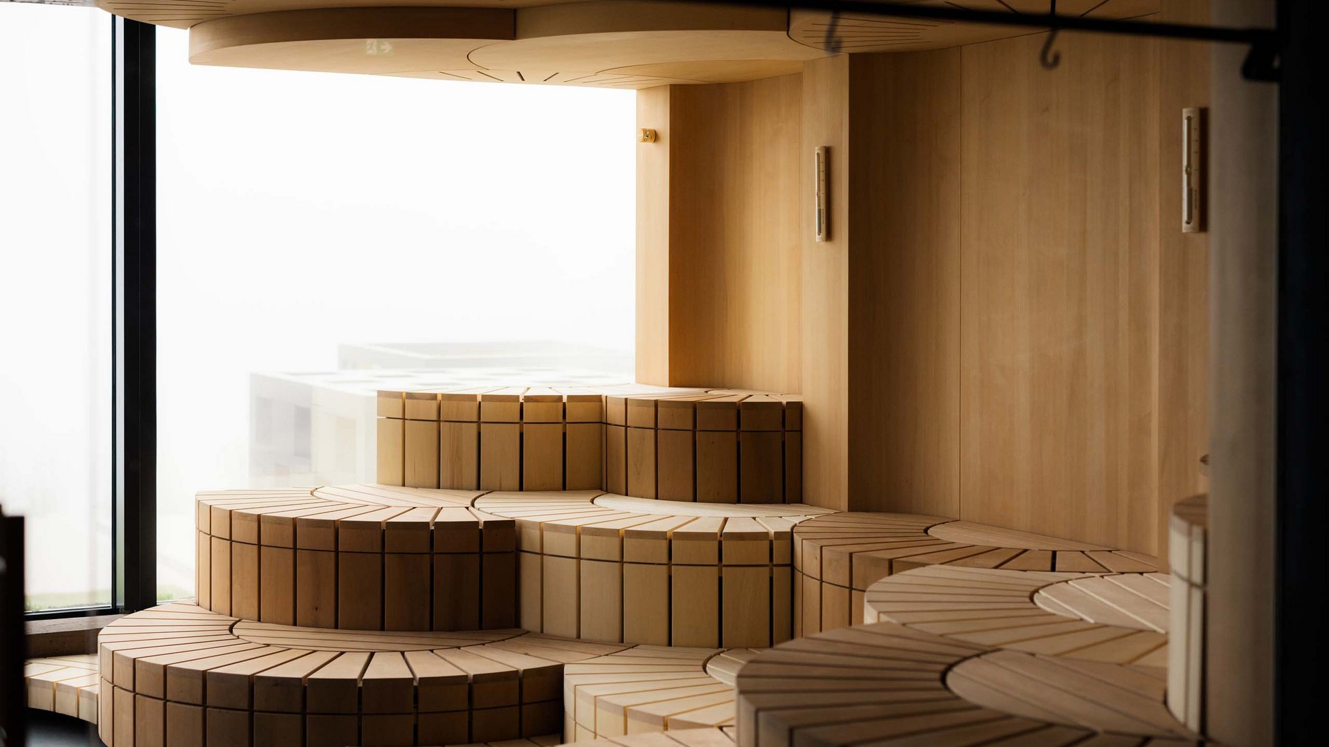 MOHR life resort Bildergalerie Modernes, gestuftes Holzsofa in hellen natürlichen Tönen vor Fenster