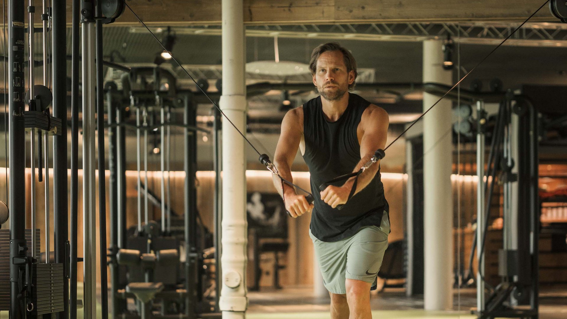 MOHR life resort Bildergalerie Mann trainiert mit Kabelzug in modernem Fitnessstudio
