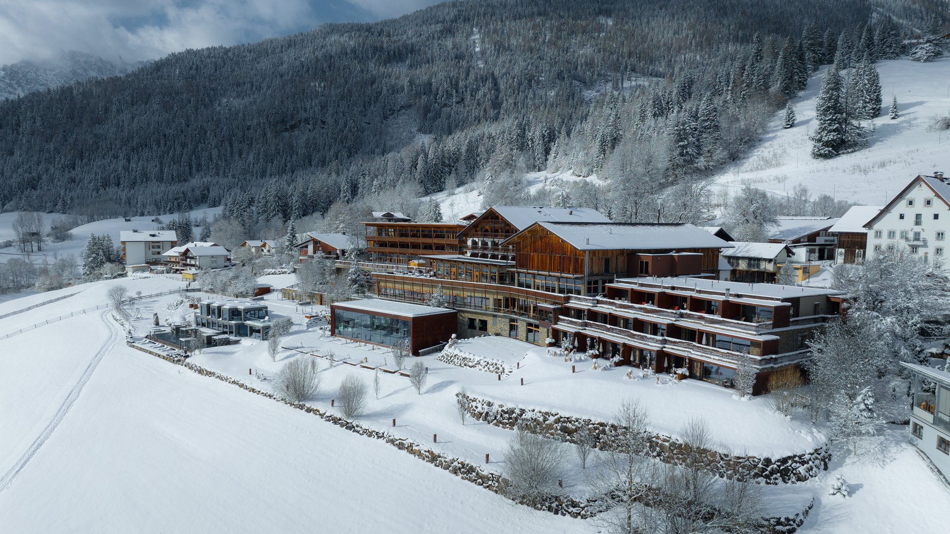 Wellness und Luxus: Ihr Hotel in Tirol Schneebedeckte Gebäude am Waldrand in einer Winterlandschaft