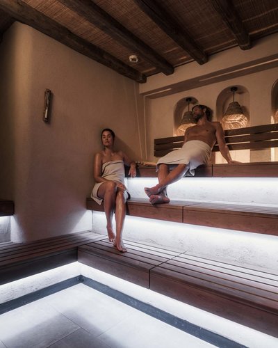 Skifahren in Lermoos und im Skigebiet Zugspitze Zwei Personen entspannen in einem beleuchteten Holzsaunainterieur