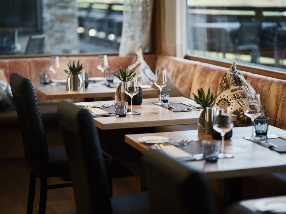 MOHR Genuss im Sporthotel in Österreich Eleganter eingedeckter Restaurantbereich mit Holztischen und Ledersesseln