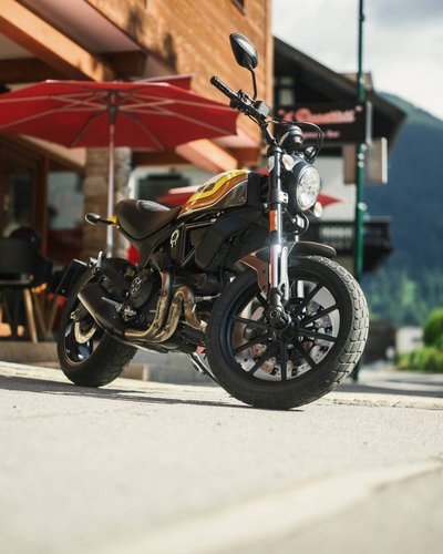 Zahlreiche Ausflugsziele rund um Lermoos Schwarzes und gelbes Motorrad auf Gehweg vor Café mit rotem Sonnenschirm