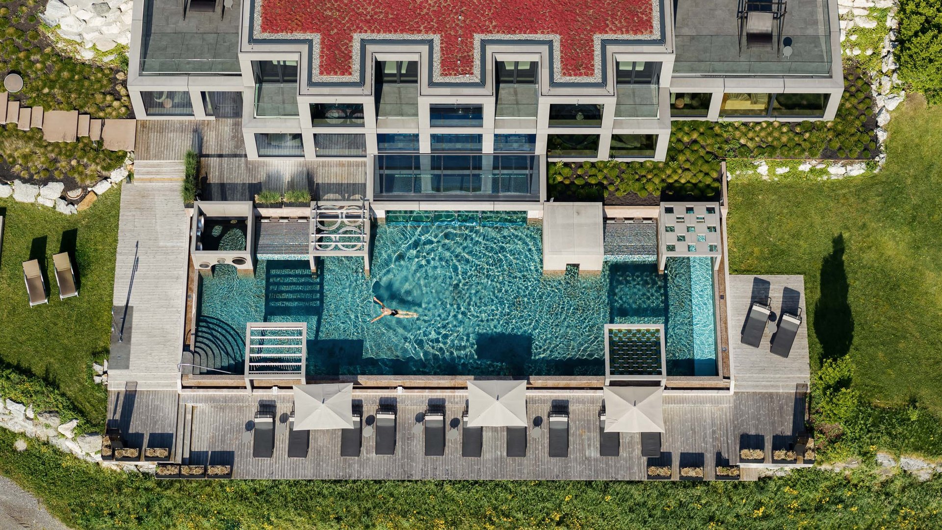 Großzügig und exklusiv: Ihr Wellnessurlaub in Tirol Luftaufnahme eines modernen Hauses mit Pool und Liegestühlen im Garten