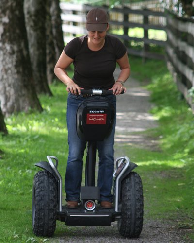 Wellness und Luxus: Ihr Hotel in Tirol Frau fährt Segway auf einem Waldweg neben einem Zaun