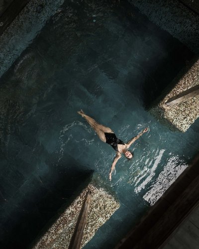 MOHR life resort – wunderbares Wellnesshotel in Lermoos Frau im schwarzen Badeanzug liegt entspannt auf dem Wasser in einem Pool