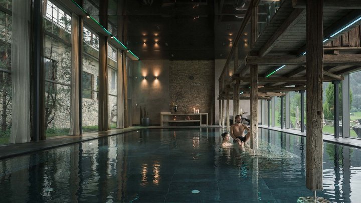 Wellness und Luxus: Ihr Hotel in Tirol Innenblick auf einen Pool mit zwei Personen und Holzbalken im modernen Spa