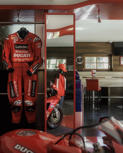 MOHR Sport bedeutet MOHR fun. Rotes Ducati-Rennanzug und Motorrad in einem Café mit Sitzbereich