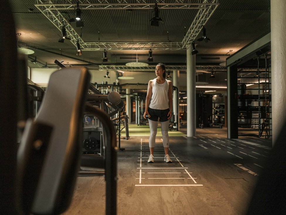 MOHR intensity: Sporturlaub in Österreich Frau im Fitnessstudio hält Hantel und steht auf markiertem Boden