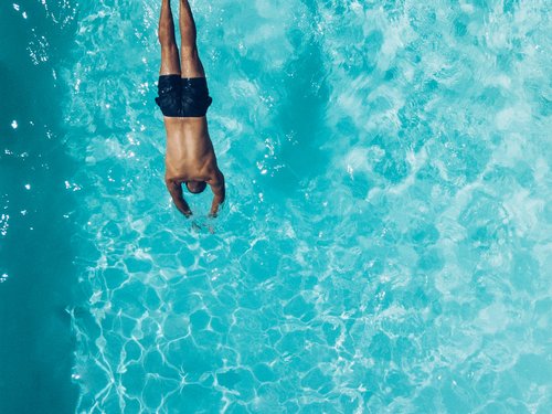 Sehenswürdigkeiten rund um Lermoos Mann taucht kopfüber in einen klaren blauen Pool