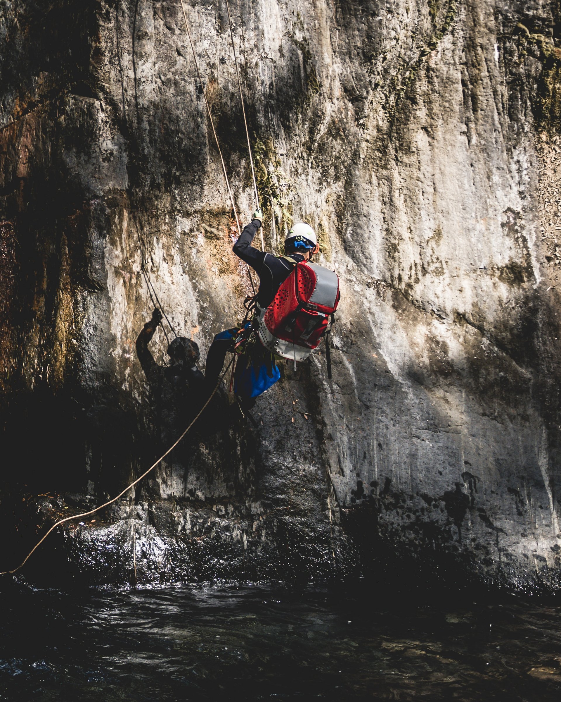 Tour de MOHR Person klettert an felsiger Klippe neben Wasserfall