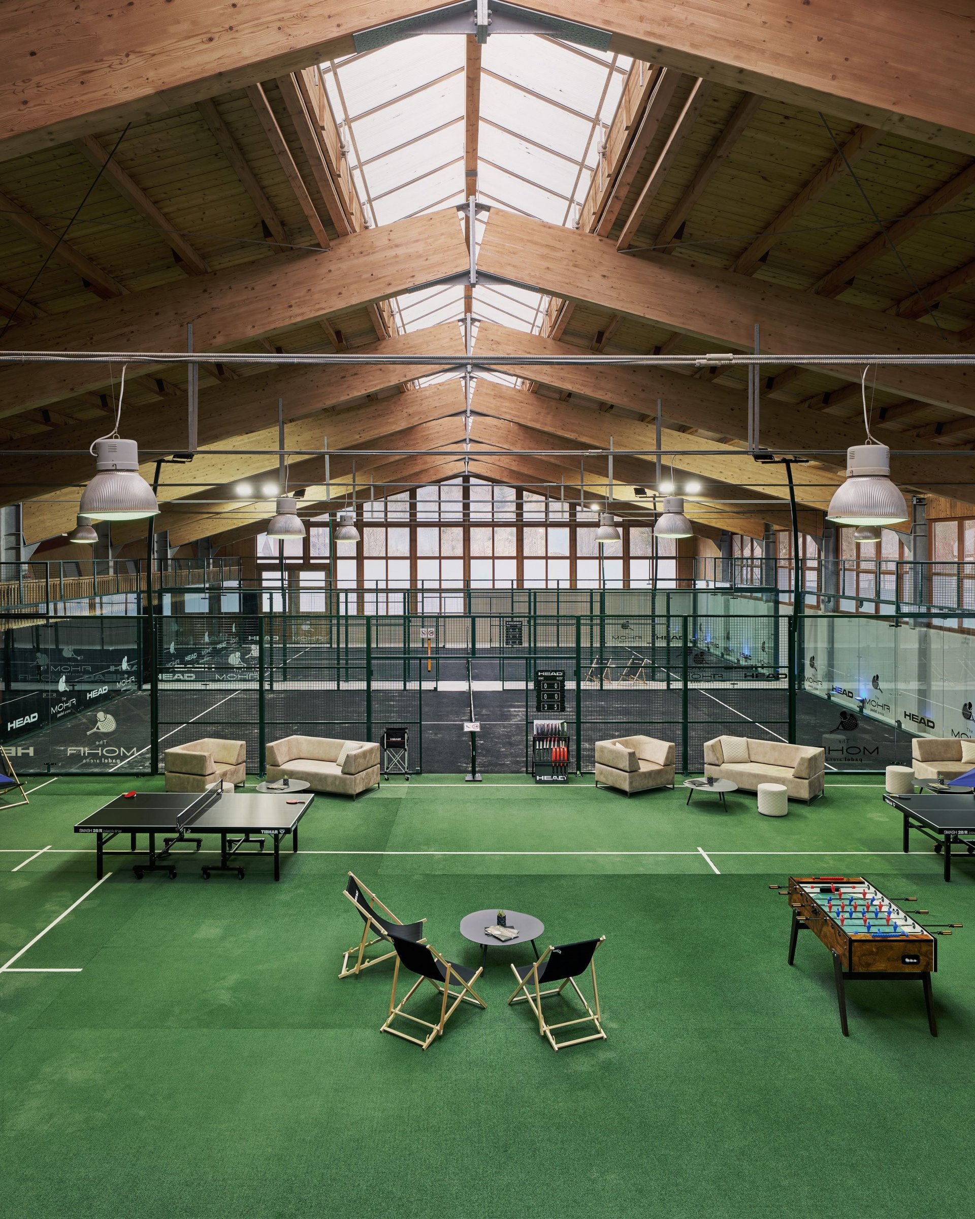Wellness und Luxus: Ihr Hotel in Tirol Indoor-Padel-Tennisplätze mit Spielern und Sitzbereich auf grünem Teppich