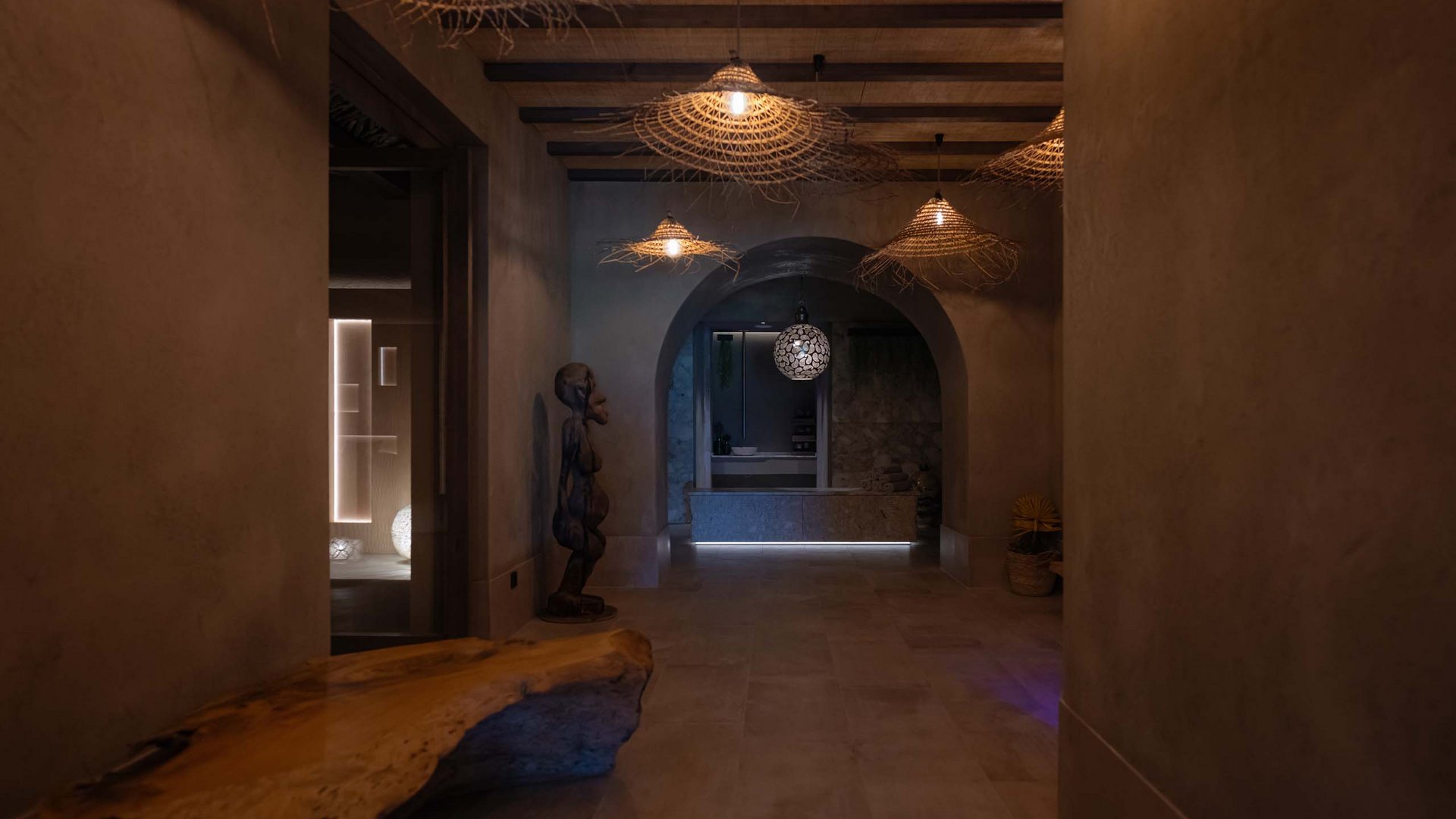 MOHR life resort Bildergalerie Dunkler Flur mit Holzbank, Skulptur und dekorativen Lampen