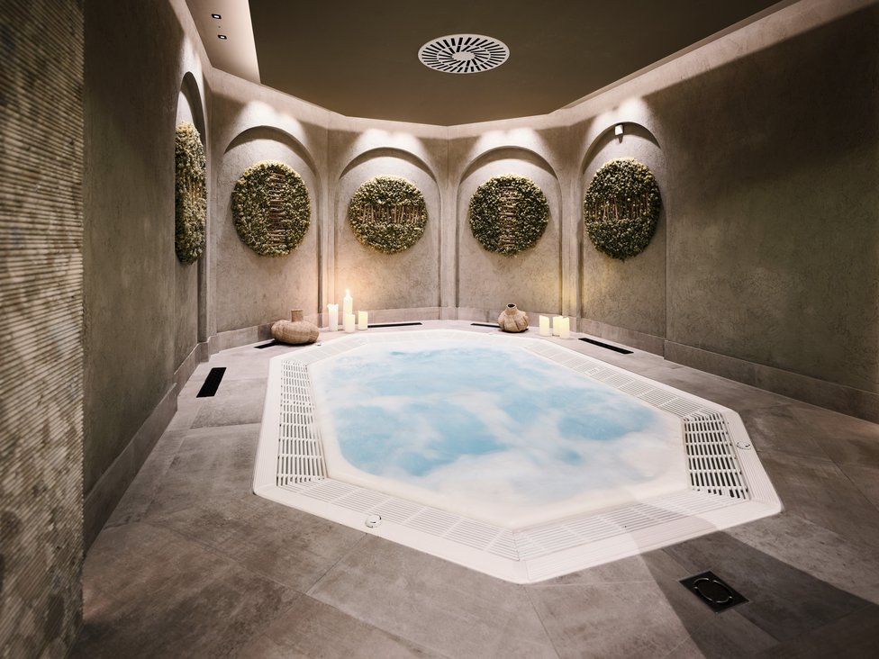 Großzügig und exklusiv: Ihr Wellnessurlaub in Tirol Moderner Whirlpool in entspannendem Spa-Raum mit Kerzen und Wanddekorationen