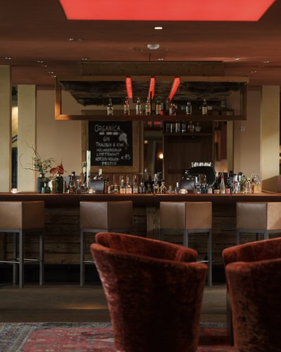 MOHR Genuss im Sporthotel in Österreich Gemütliche Bar mit Sesseln und Holzmöbeln im warmen Licht